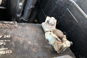 Close-up of a car battery terminal showing significant corrosion and buildup.